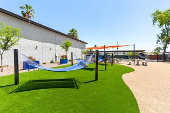 A playground with a blue hammock and a green hammock.